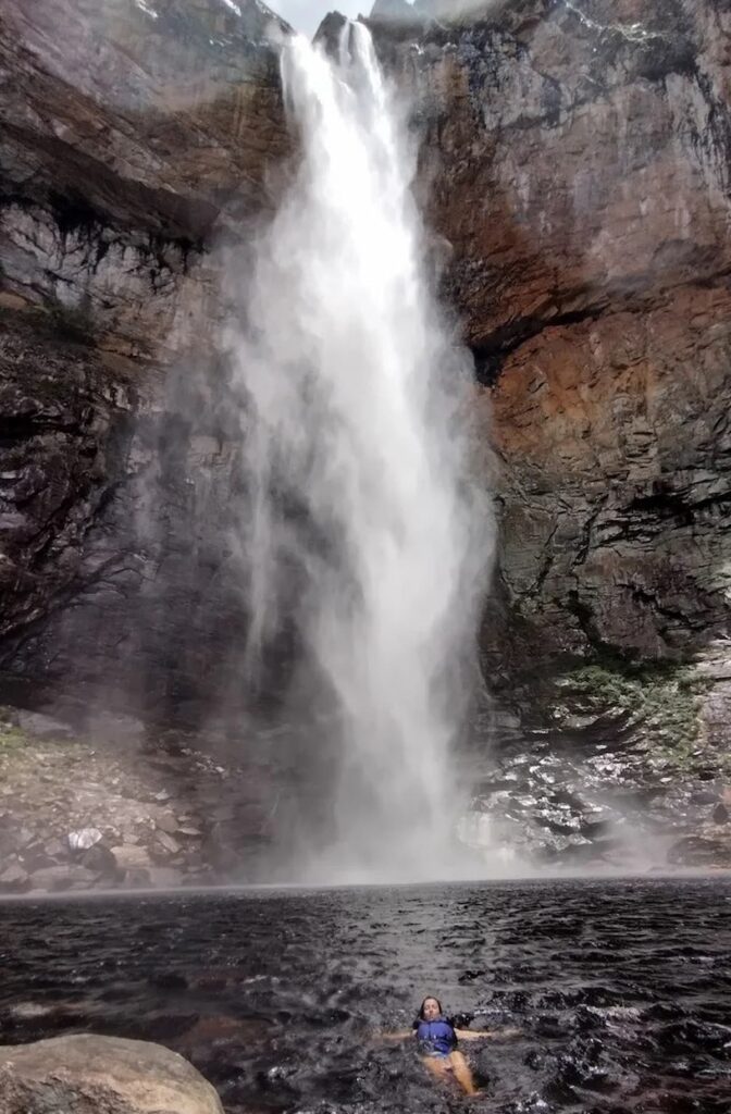magem mostra turista se refrescando na Cachoeira do Tabuleiro, Minas Gerais.